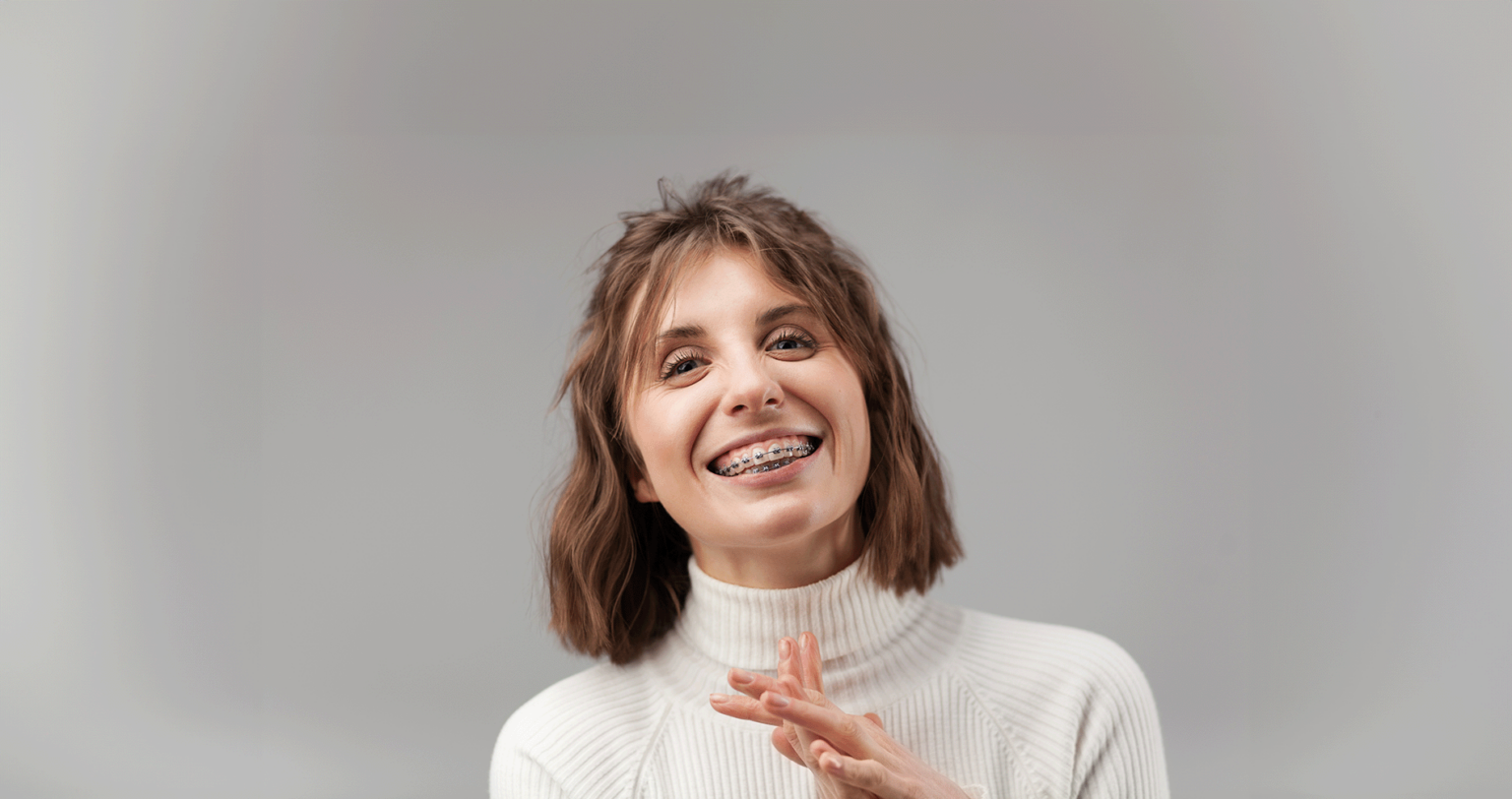 Young adult with braces in Minnetonka, MN beaming in a white turtleneck