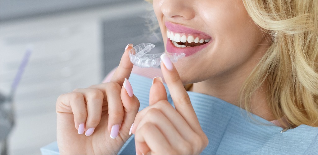 Young woman inserting clear aligner tray at her orthodontist in Minnetonka
