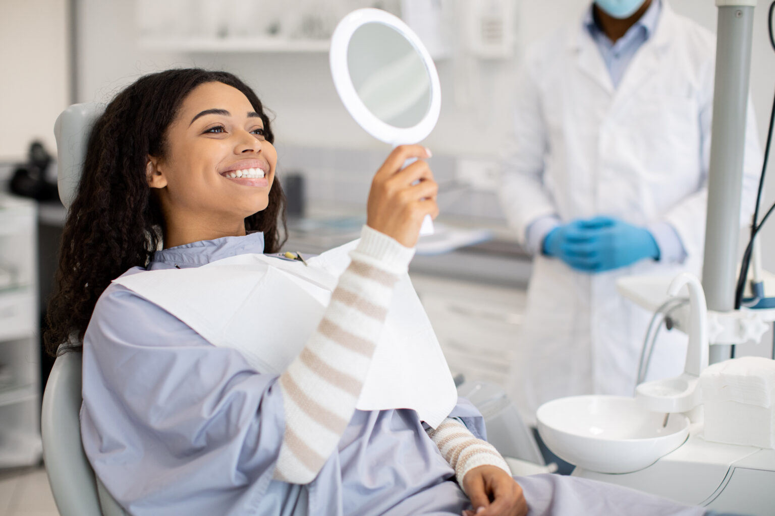 Happy Patient Looking At Mirror After Dental Treatment In Clinic