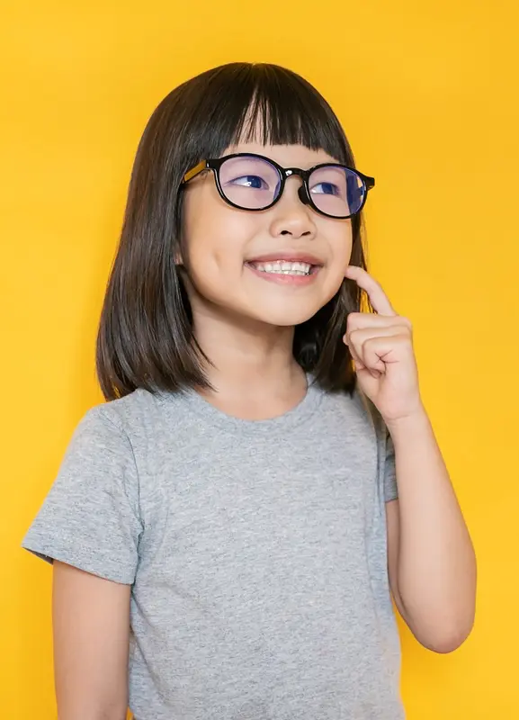 Adorable girl with glasses pointing at her teeth